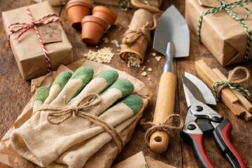 Verschiedene Gartengeräte und kleine Geschenkideen auf einem Holztisch